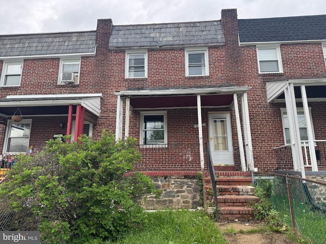 townhome / multi-family property with fence, cooling unit, mansard roof, and brick siding