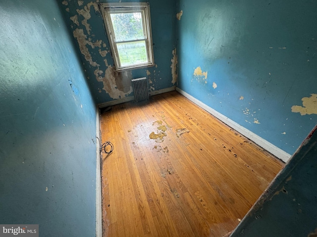 empty room featuring wood-type flooring and radiator heating unit