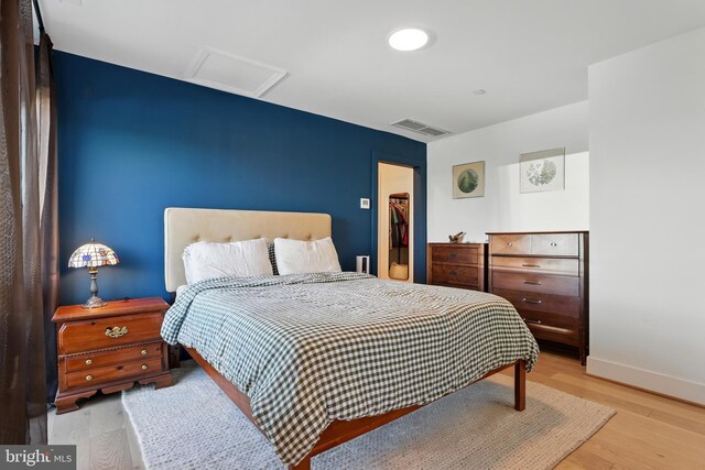 bedroom featuring attic access, wood finished floors, and baseboards