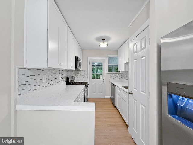 7905 Greenleaf Rd, Landover, MD 20785 - kitchen featuring stainless steel appliances, white cabinets, decorative backsplash, and light wood-type flooring
