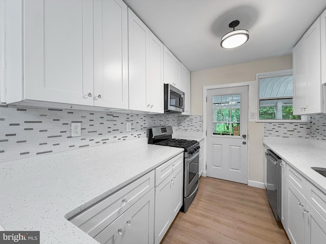 7905 Greenleaf Rd, Landover, MD 20785 - kitchen featuring appliances with stainless steel finishes, decorative backsplash, white cabinetry, light stone countertops, and light wood-style floors