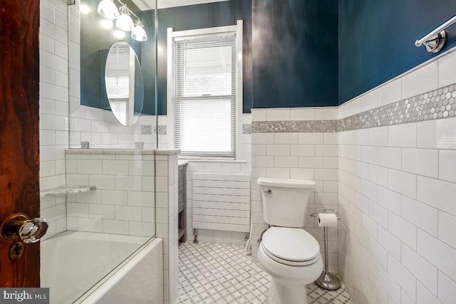 full bath featuring tile walls, a wainscoted wall, and toilet