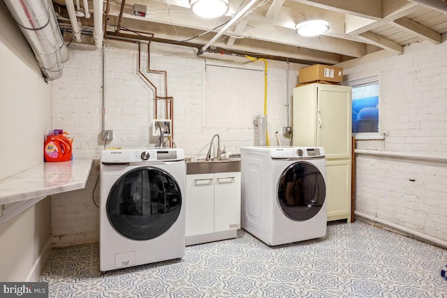 laundry room with a sink, washing machine and dryer, and brick wall