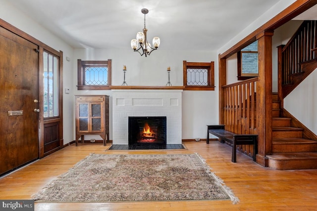 living room with a fireplace, wood finished floors, baseboards, a chandelier, and stairs