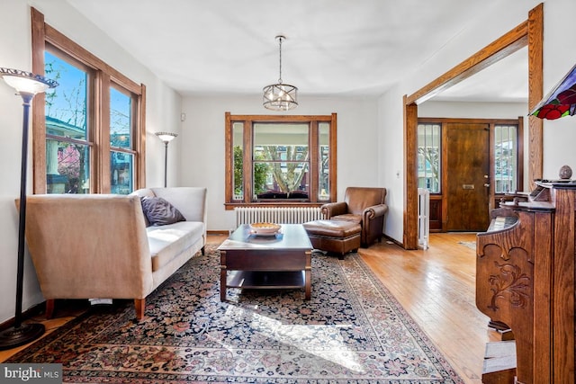 sitting room featuring light wood-style floors, radiator, and baseboards