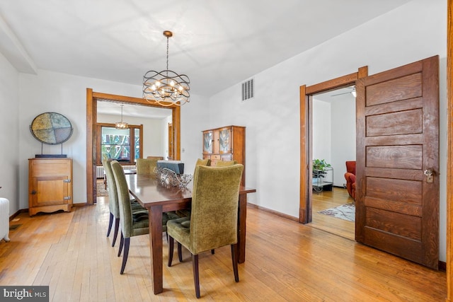 dining space featuring a chandelier, baseboards, visible vents, and light wood-style flooring