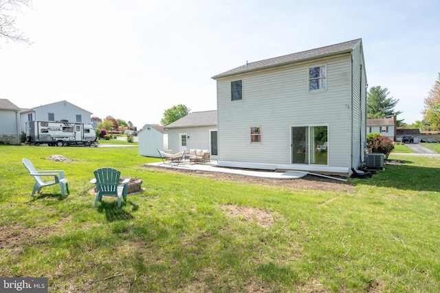 back of property with a lawn, cooling unit, a fire pit, and a patio area