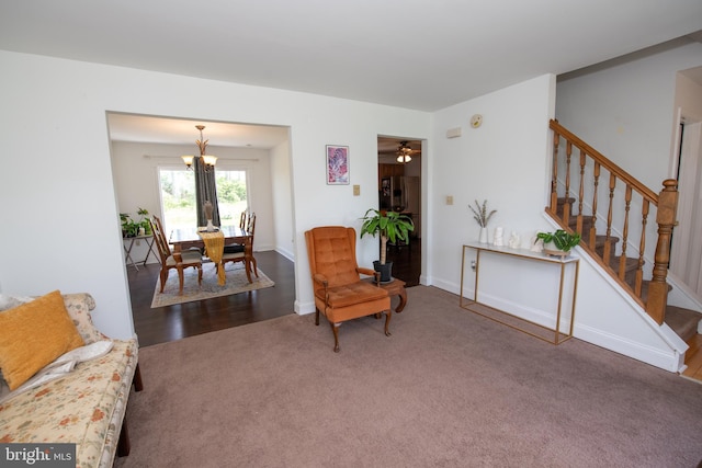 living area featuring carpet floors, stairs, and a notable chandelier