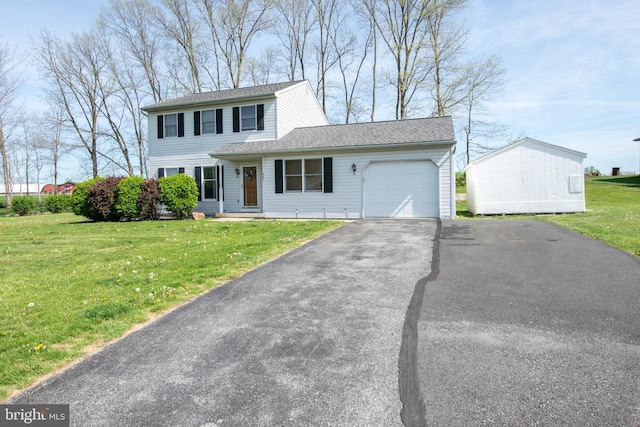 traditional-style house featuring roof with shingles, an attached garage, a front yard, and aphalt driveway