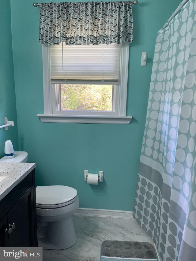 bathroom featuring toilet, vanity, a shower with curtain, marble look tiles, and baseboards