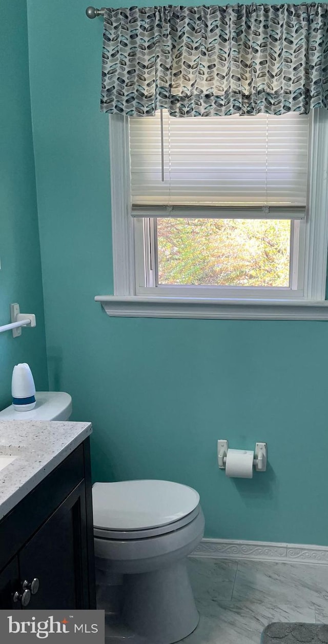 half bathroom with toilet, vanity, and baseboards