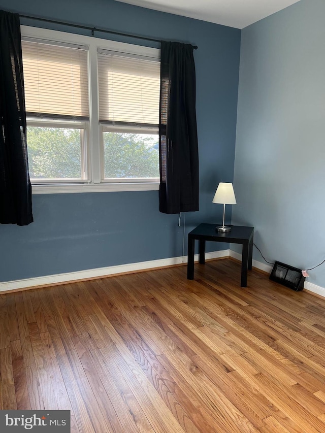 unfurnished room with baseboards and wood finished floors