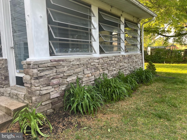 view of side of home with stone siding and a lawn