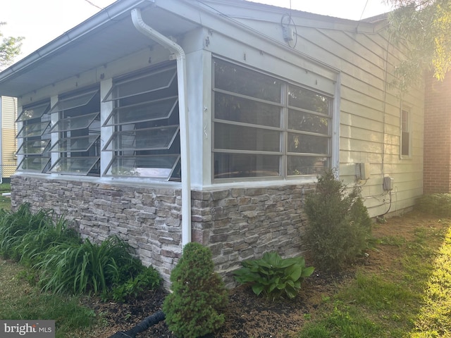 view of home's exterior featuring stone siding and a sunroom