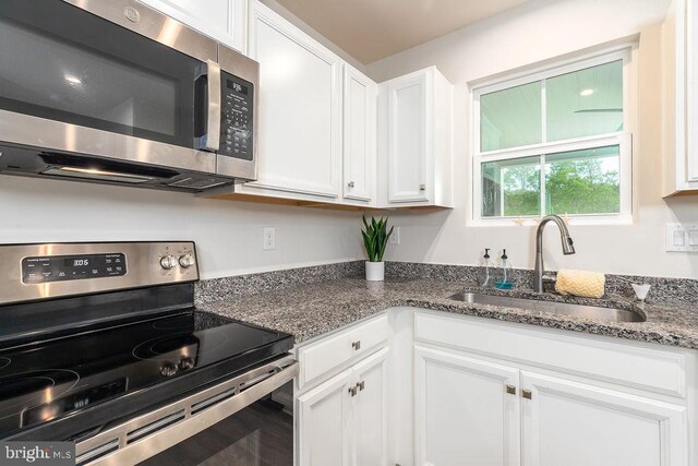 28020 Dew Drop Ln, Millville, DE 19967 - kitchen with white cabinets, appliances with stainless steel finishes, a sink, and dark stone countertops