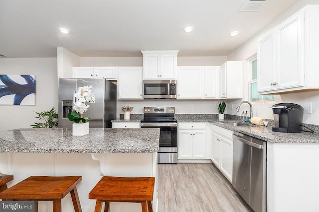 28020 Dew Drop Ln, Millville, DE 19967 - kitchen with a sink, stainless steel appliances, white cabinetry, a kitchen bar, and visible vents