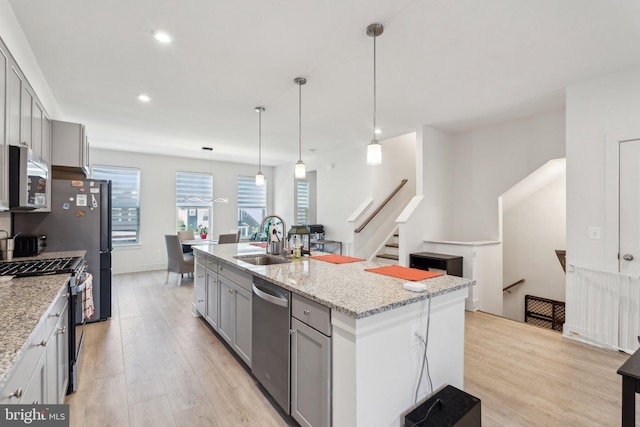 1490 Meadowlark Glen Rd, Dumfries, VA 22026 - kitchen featuring appliances with stainless steel finishes, a sink, gray cabinets, light wood finished floors, and a center island with sink