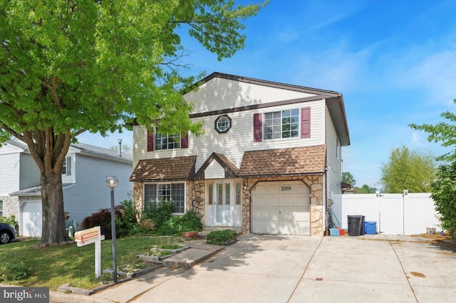 traditional-style house with an attached garage, fence, driveway, and stone siding