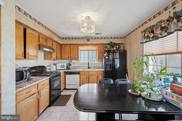 kitchen featuring a sink, light countertops, black appliances, and under cabinet range hood