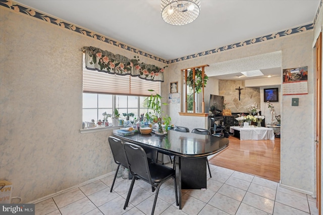 tiled dining space with an inviting chandelier, baseboards, and wallpapered walls