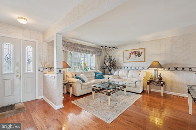 foyer with baseboards, wallpapered walls, wood finished floors, and visible vents
