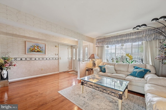 living area featuring baseboards, wood finished floors, and wallpapered walls