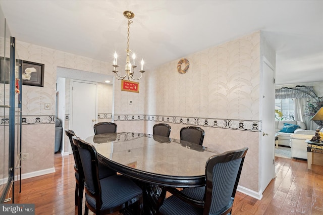 dining room with an inviting chandelier, baseboards, wallpapered walls, and hardwood / wood-style flooring