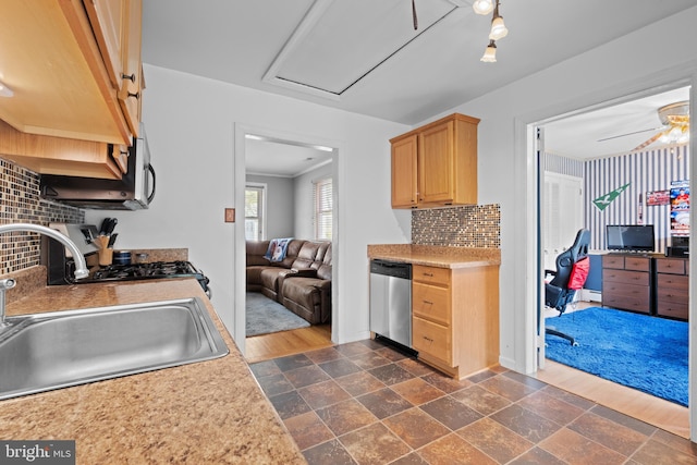 kitchen with a sink, stone tile floors, backsplash, light countertops, and appliances with stainless steel finishes
