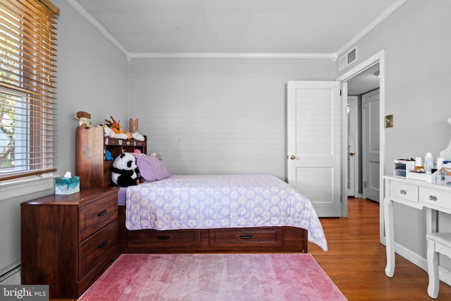 bedroom with crown molding, visible vents, and wood finished floors