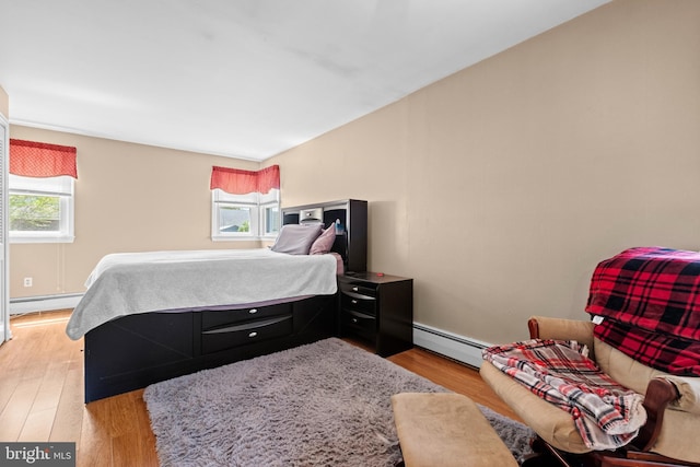 bedroom featuring multiple windows, light wood-type flooring, baseboard heating, and a baseboard heating unit