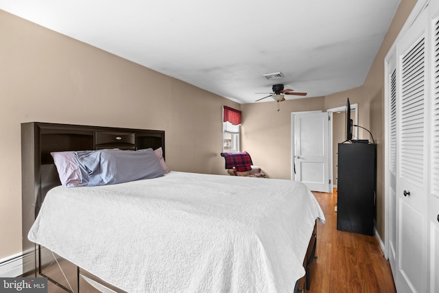 bedroom with wood finished floors, a ceiling fan, a closet, visible vents, and baseboards