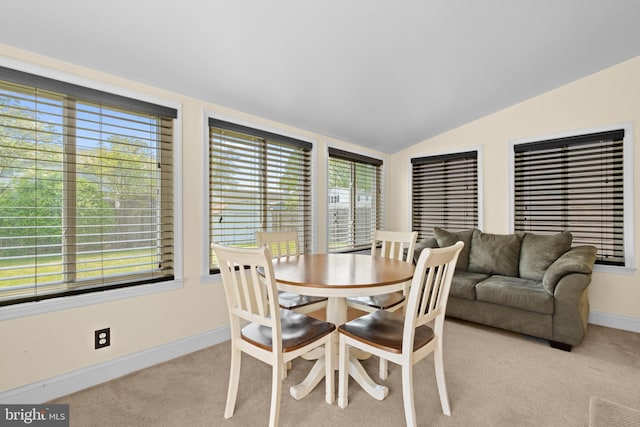 dining room with lofted ceiling, light carpet, plenty of natural light, and baseboards
