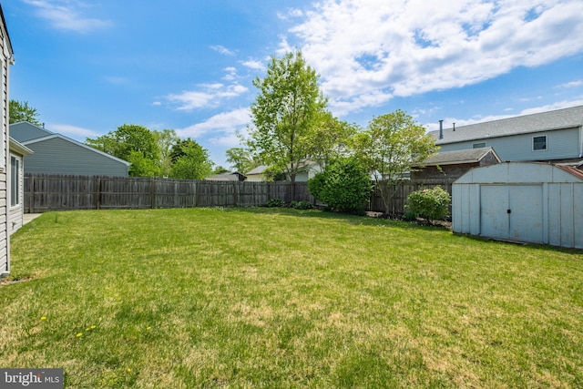 view of yard with a fenced backyard, an outbuilding, and a storage shed