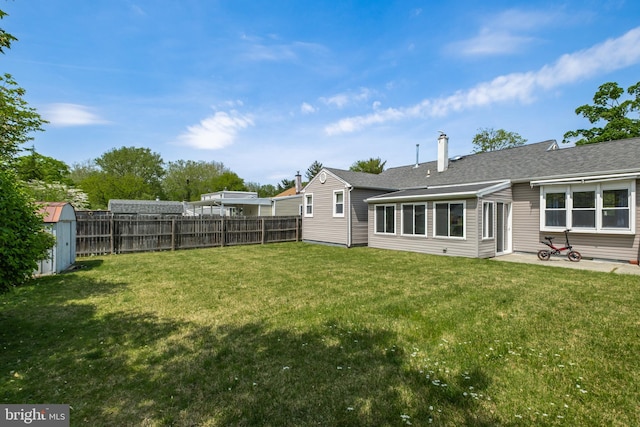 back of property with a yard, fence, a storage shed, and a patio