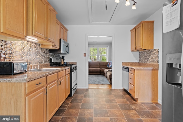 kitchen with a toaster, baseboards, a sink, tasteful backsplash, and appliances with stainless steel finishes