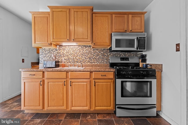 kitchen with a sink, stainless steel appliances, decorative backsplash, and baseboards