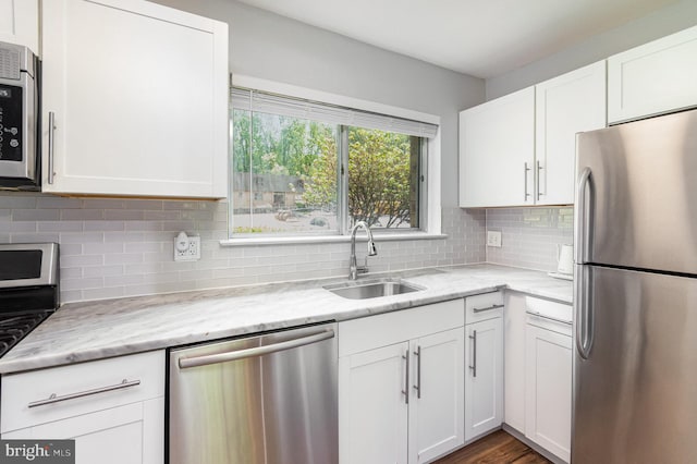 kitchen featuring a sink, white cabinetry, backsplash, and stainless steel appliances