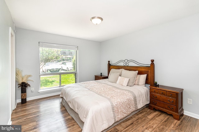 bedroom featuring baseboards, multiple windows, and wood finished floors