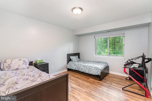 bedroom with baseboards, visible vents, and light wood-type flooring