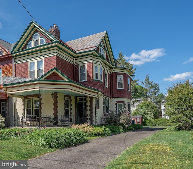 victorian-style house featuring a porch and a chimney