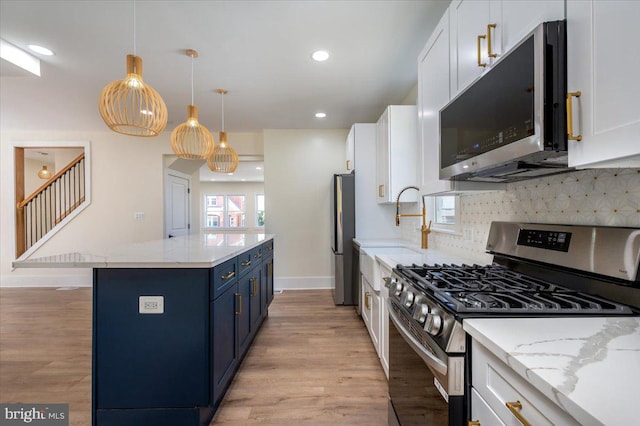 kitchen featuring light wood-style floors, blue cabinets, a center island, and stainless steel appliances