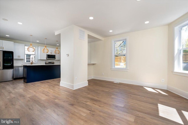 unfurnished living room featuring a sink, baseboards, recessed lighting, and wood finished floors