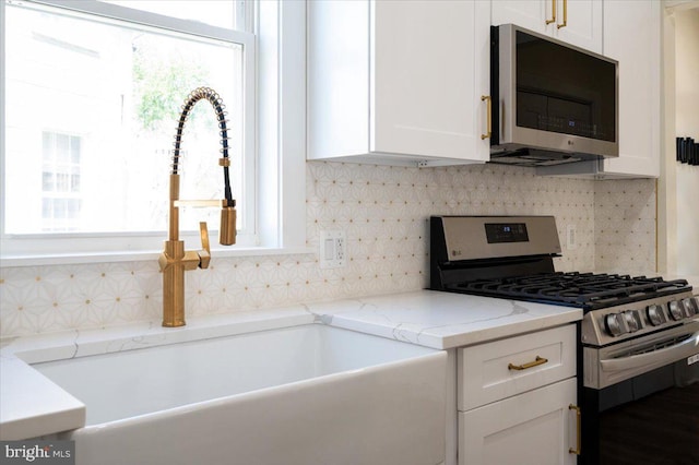 kitchen with white cabinets, backsplash, stainless steel appliances, and a wealth of natural light