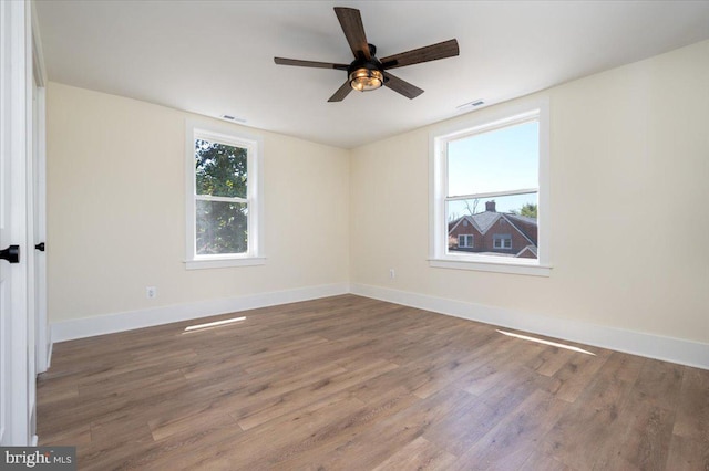 empty room featuring visible vents, a ceiling fan, baseboards, and wood finished floors