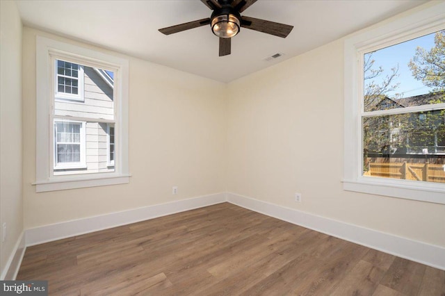 empty room with visible vents, baseboards, ceiling fan, and wood finished floors