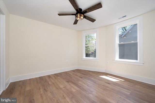 empty room featuring baseboards, a ceiling fan, wood finished floors, and visible vents