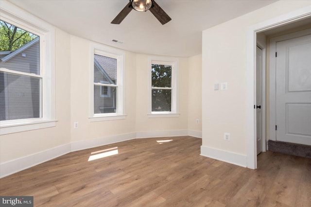 unfurnished room with visible vents, baseboards, ceiling fan, and wood finished floors