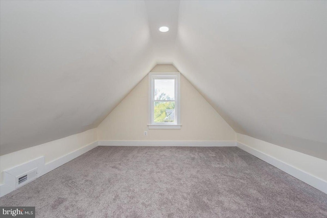 additional living space featuring carpet floors, baseboards, lofted ceiling, and visible vents