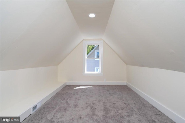 additional living space with baseboards, visible vents, carpet flooring, and lofted ceiling