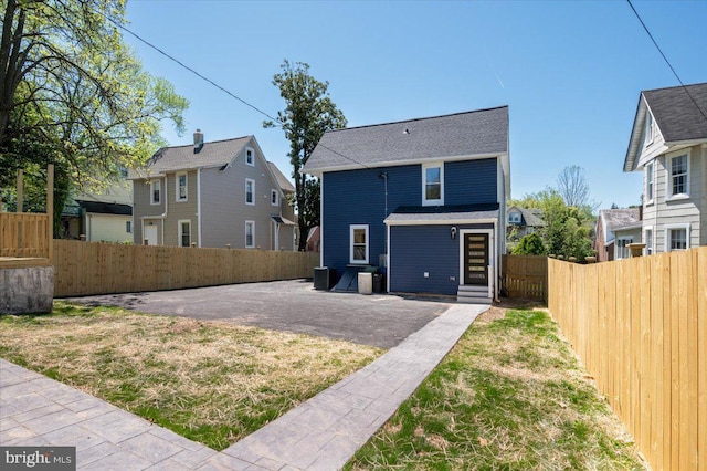 back of property featuring a lawn, a fenced backyard, and entry steps